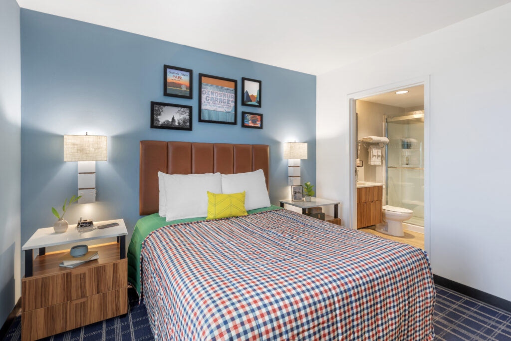 Single queen bed suite view with comfortable bedding and view of en-suite bathroom.