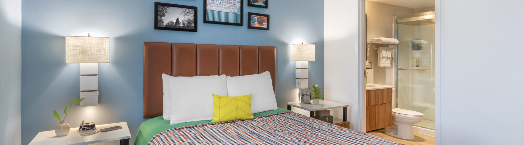 Single queen bed suite view with comfortable bedding and view of en-suite bathroom.