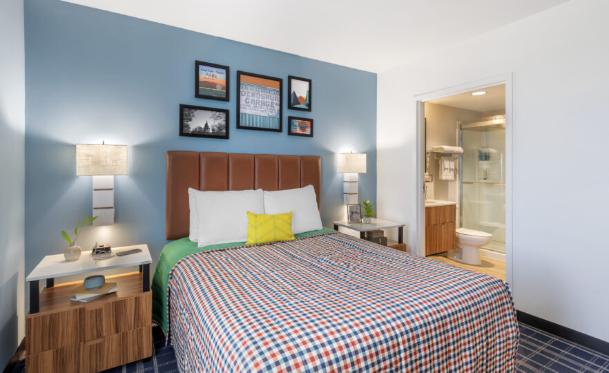 Single queen bed suite view with comfortable bedding and view of en-suite bathroom.