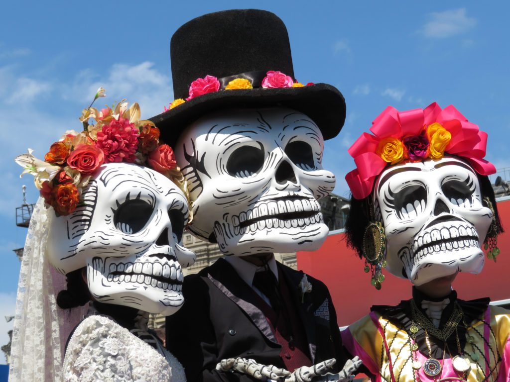 Three participants in the Day of the Dead parade in Austin dressed in traditional attire. 