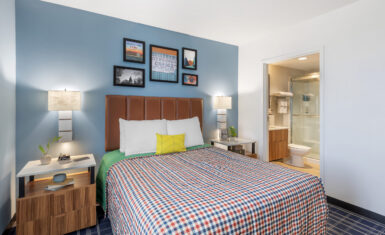 Single queen bed suite view with comfortable bedding and view of en-suite bathroom.